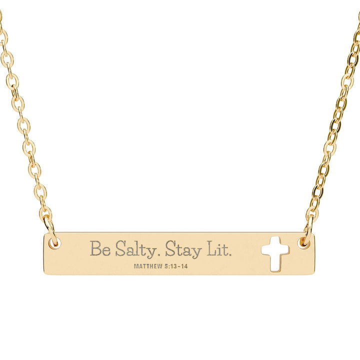Gold necklace with bar pendant and cross, featuring 'Be Salty. Stay Lit.' text.